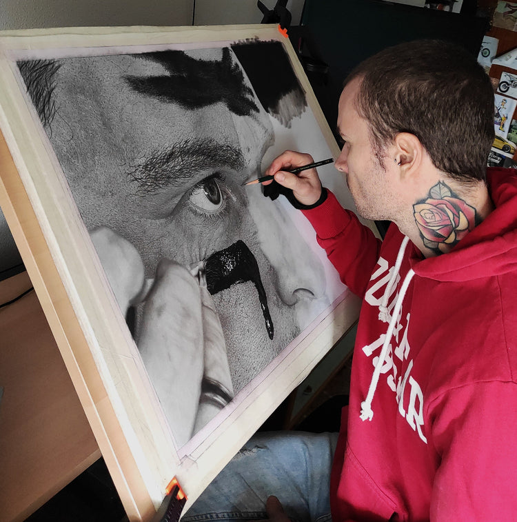 El artista David Mateo en su estudio trabajando en un dibujo original de arte hiperrealista.