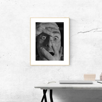 Fotografía artística en blanco y negro de un hombre con la boca y los ojos abiertos. La composición de las manos añade un fuerte elemento de tensión y narrativa.