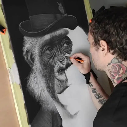 El artista David Mateo trabajando en un dibujo a lápiz en hiperrealismo a carboncillo de un gorila elegante con sombrero de copa. Muestra el proceso de creación y la técnica de alto contraste.