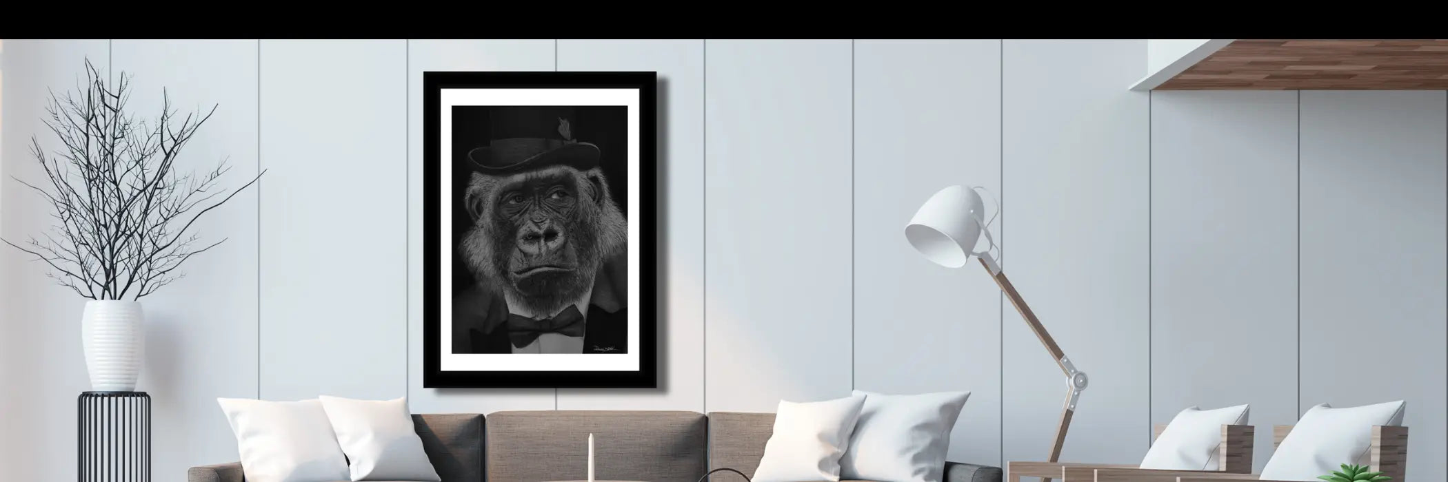 Banner principal con una lámina en blanco y negro de un gorila elegante con sombrero, colgada sobre un sofá en un salón moderno.