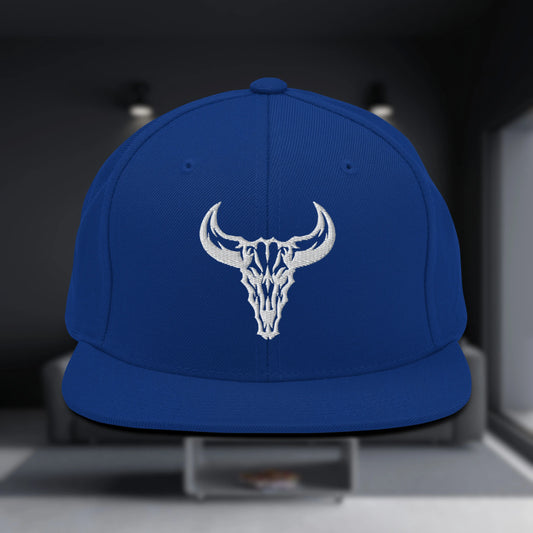 Gorra Snapback de color azul eléctrico con visera plana, con el logo de la calavera de toro bordado en blanco. Accesorio esencial para el estilo streetwear.