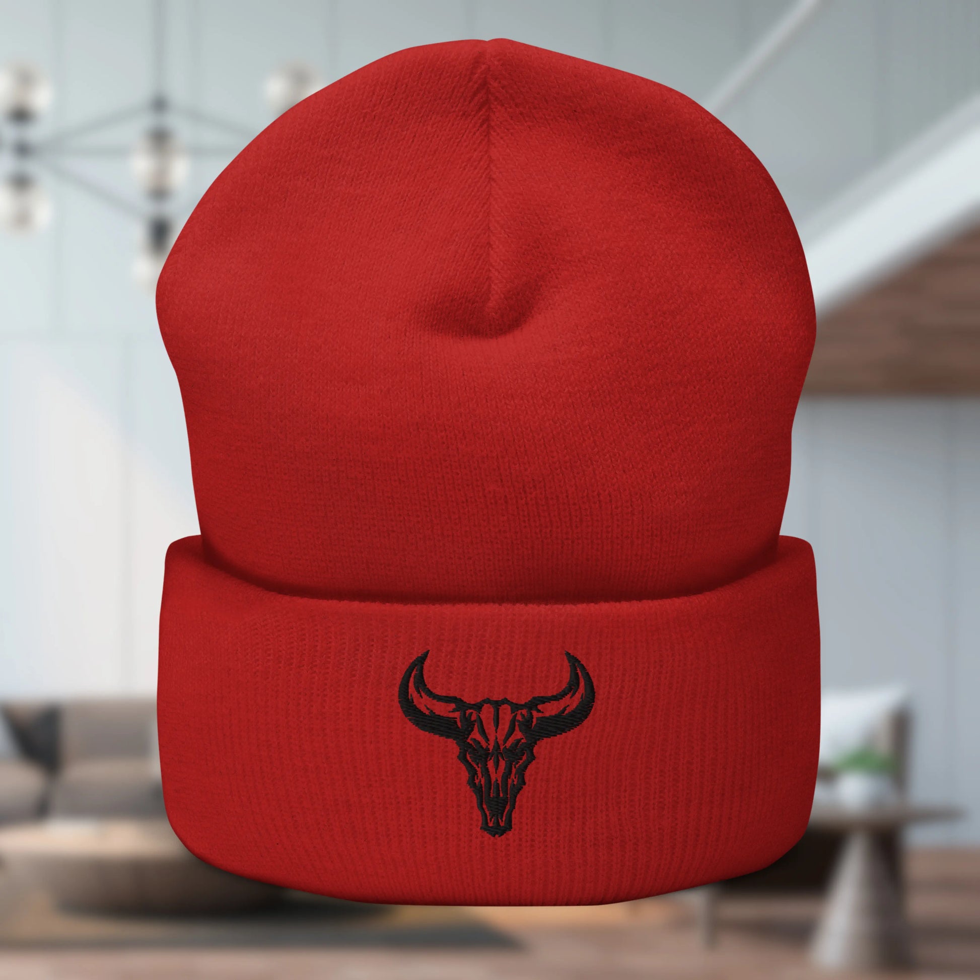 Primer plano de un gorro beanie color naranja mandarina con un logo de cráneo de toro bordado en la solapa inferior. Producto de David Mateo.