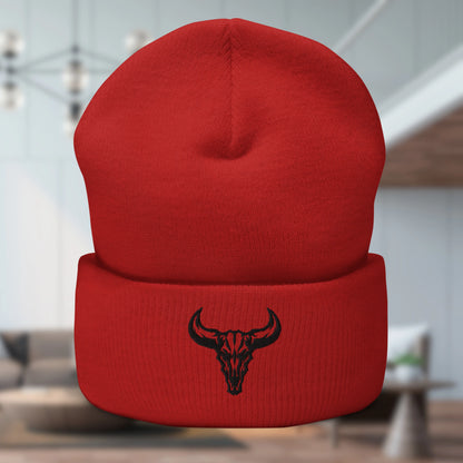 Primer plano de un gorro beanie color naranja mandarina con un logo de cráneo de toro bordado en la solapa inferior. Producto de David Mateo.
