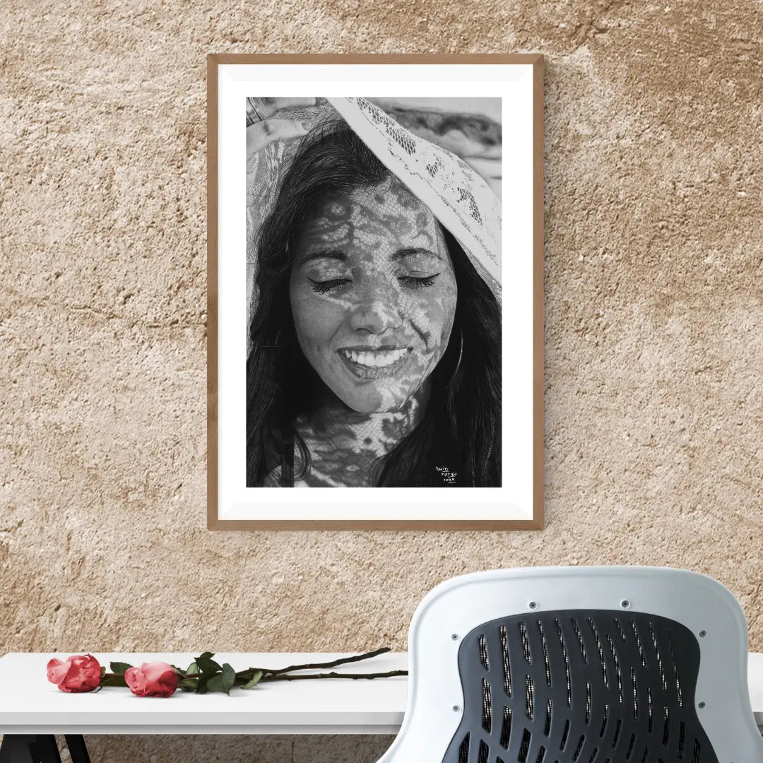 Obra de David Mateo Art. Reproducción de alta calidad de un retrato de mujer, con un marco blanco, sobre una estantería junto a decoración botánica.