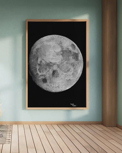 Lámina enmarcada en blanco, sobre una estantería blanca. Muestra un dibujo monocromático de la luna llena en un fondo negro, con un jarrón y una hoja de planta a la izquierda.