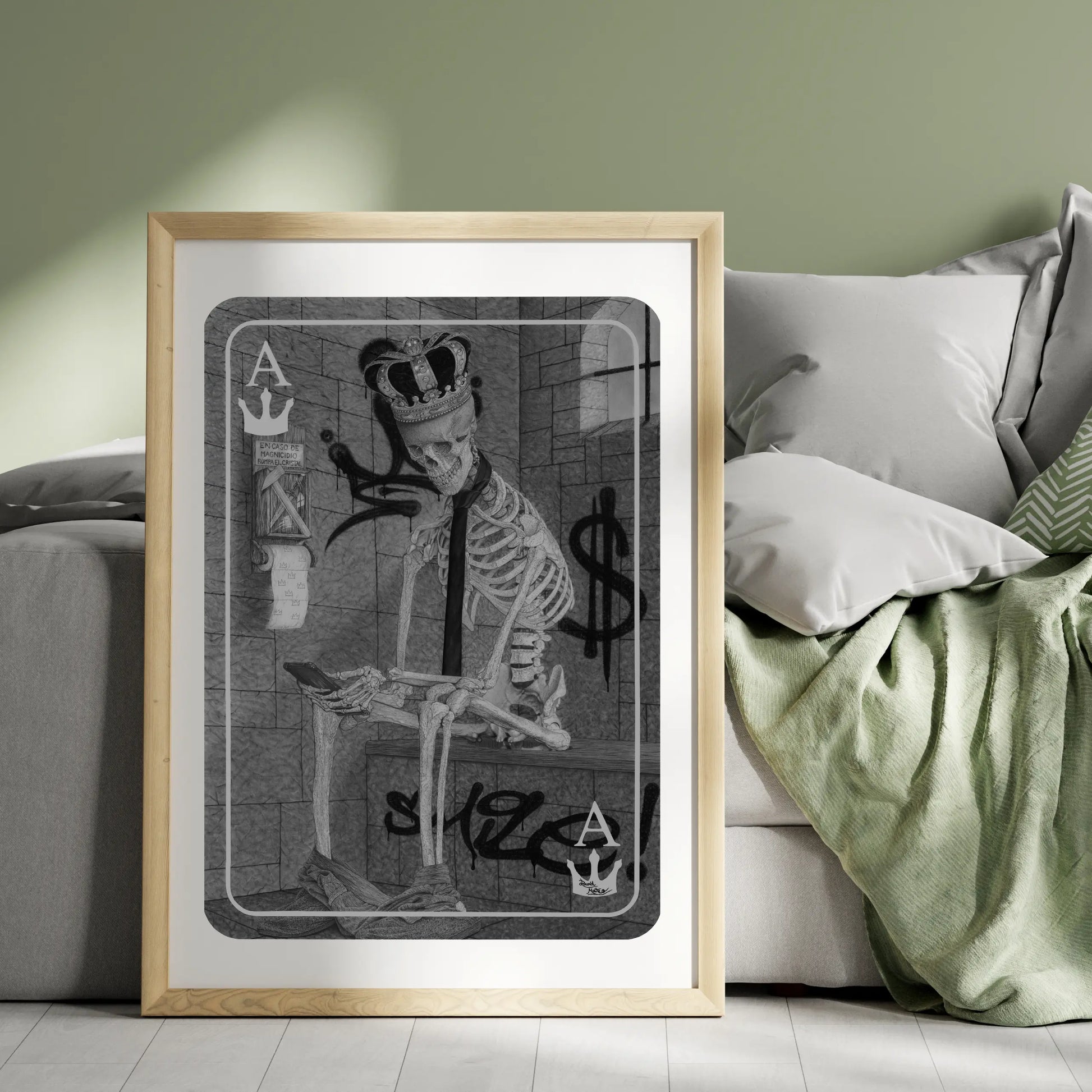 Lámina vertical colocada en el suelo, con un dibujo de un esqueleto vestido con una corona y corbata, sentado sobre un bloque en una habitación de ladrillo simulado.