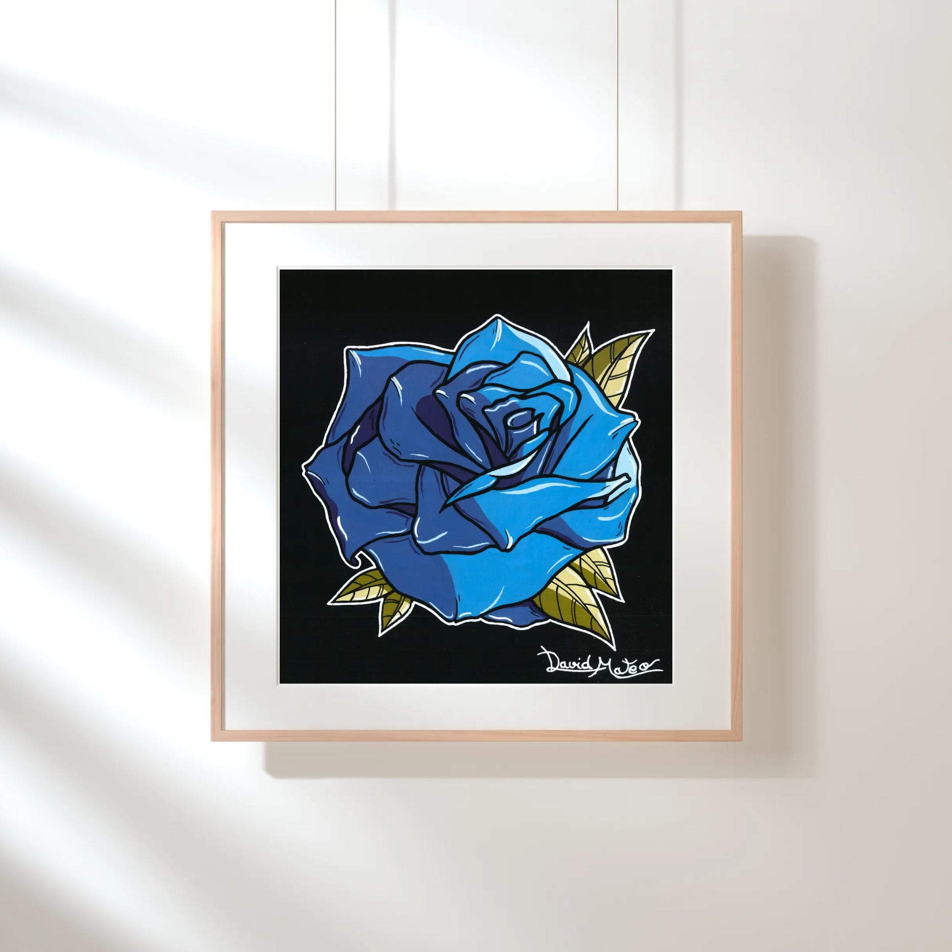 Lámina enmarcada en madera, sobre una pared verde pálido con sombras de luz solar. Muestra un dibujo a color de una rosa azul brillante sobre fondo negro.