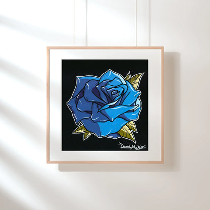 Lámina enmarcada en madera, sobre una pared verde pálido con sombras de luz solar. Muestra un dibujo a color de una rosa azul brillante sobre fondo negro.