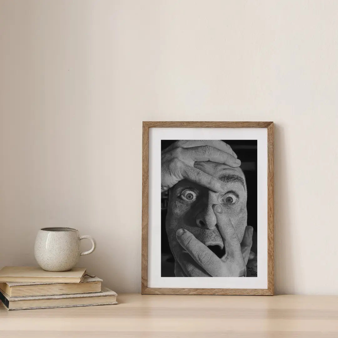 Lámina de un retrato dramático que captura la sorpresa o el terror. Manos que cubren y distorsionan el rostro, creando una expresión de emoción cruda e intensa.