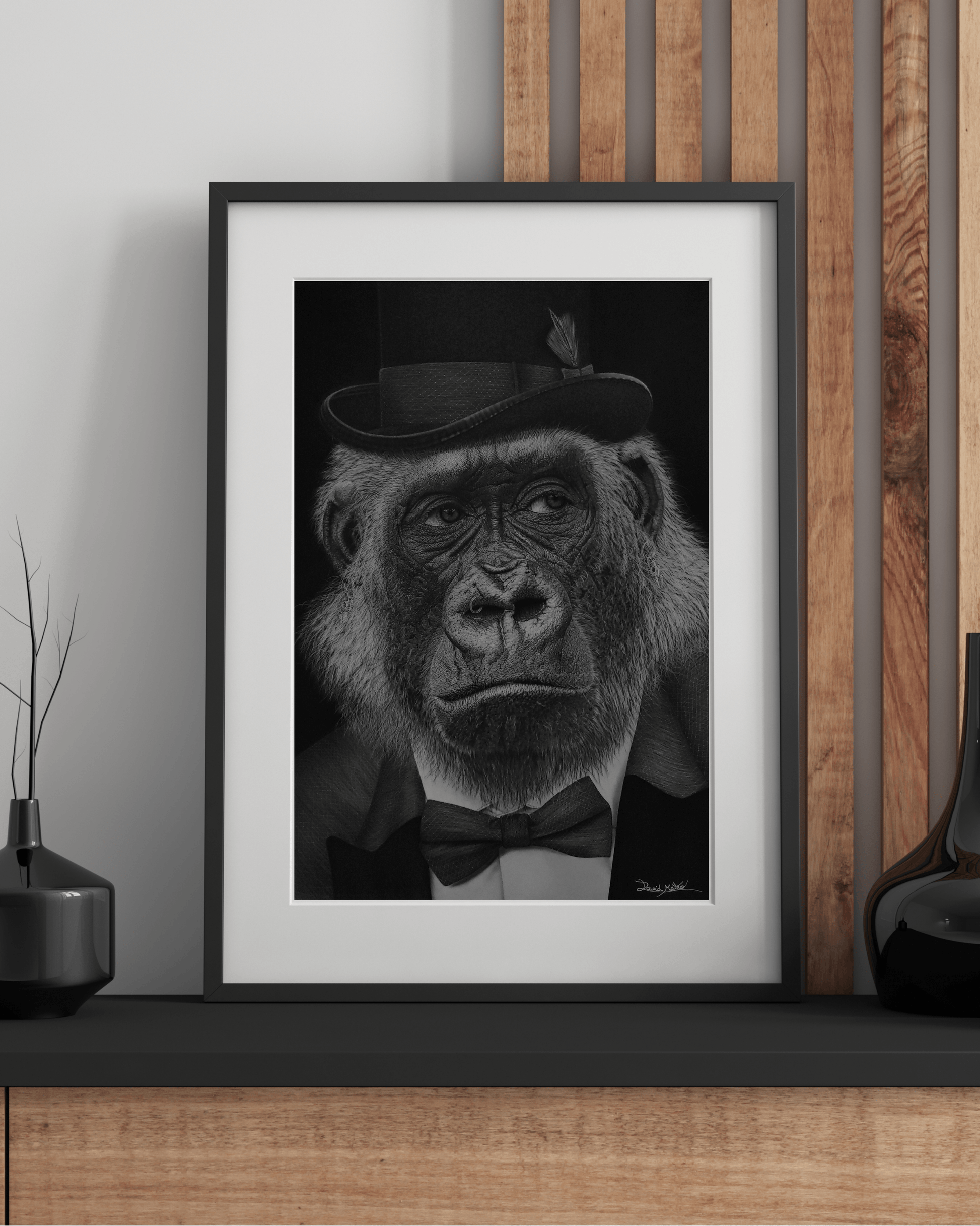 Lámina artística '¡Qué Mono!' con retrato satírico de gorila elegante en blanco y negro, enmarcada sobre mueble moderno en decoración minimalista.